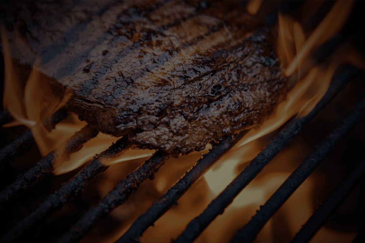 Steak searing over open flames on the grill